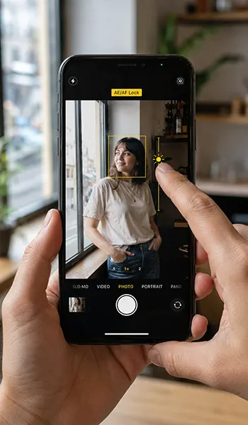 Hands use AE/AF lock on iphone while photographing a portrait.