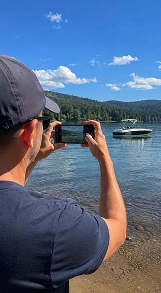 man taking a photo of a boat using his iPhone in burst mode.