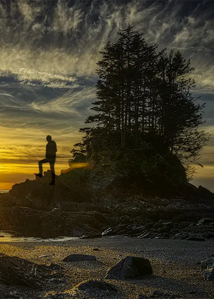 silhouette photos with phone of a person on a rocky beach